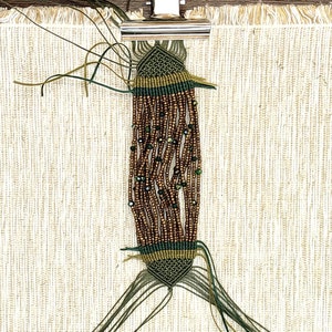 May include: A green and brown beaded bracelet with a knotted design. The bracelet is made with small brown beads and green beads with a metallic sheen.