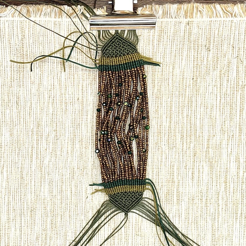 May include: A green and brown beaded bracelet with a knotted design. The bracelet is made with small brown beads and green beads with a metallic sheen.