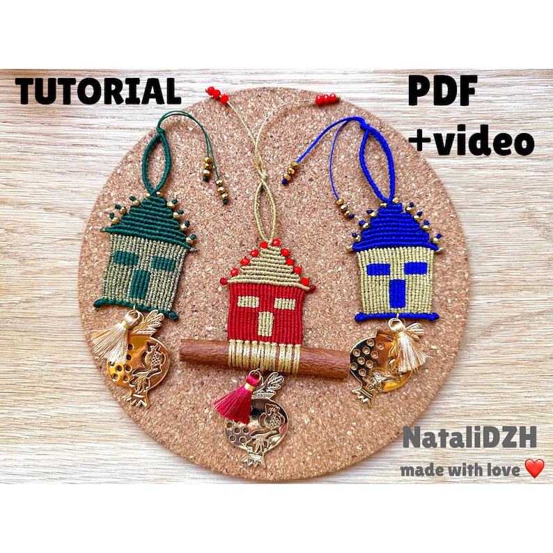Pu&ograve; includere: Tre ornamenti in macram&egrave; fatti a mano a forma di case, ognuno con uno schema di colori diverso: verde, rosso e blu. Gli ornamenti sono appesi a catene dorate e hanno frange dorate. Lo sfondo &egrave; un pannello di sughero con il testo "TUTORIAL" e "PDF + video" su di esso. Il testo "NataliDZH made with love" &egrave; anche visibile nella parte inferiore dell'immagine.