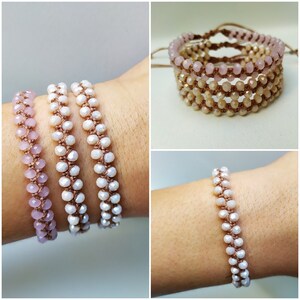 May include: Three beaded bracelets with a light pink, white, and beige color gradient. The bracelets are made with small, round beads and are tied with a brown cord.