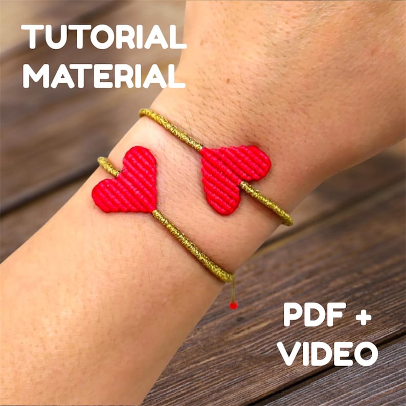 Pode incluir: Um bracelete dourado com dois pingentes de cora&ccedil;&atilde;o vermelho. O bracelete est&aacute; no pulso de uma pessoa. O texto "TUTORIAL MATERIAL" est&aacute; no topo da imagem. O texto "PDF + VIDEO" est&aacute; na parte inferior da imagem.