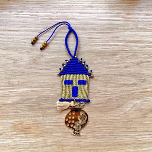 Pu&ograve; includere: Un ornamento in macram&egrave; blu e oro con un design a croce e un ciondolo a forma di melograno dorato. L'ornamento &egrave; appeso a un cordoncino blu.