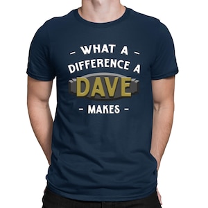 Könnte beinhalten: Ein marineblaues T-Shirt mit weißem Text, der "What a difference a Dave makes" lautet. Der Text ist von einem schwarzen und goldenen Rechteck eingerahmt.