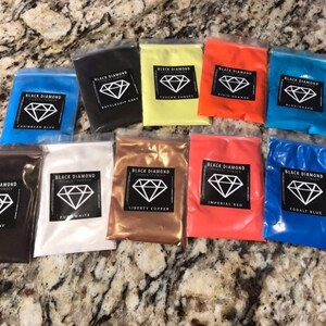 May include: Assortment of 10 small plastic bags containing pigment powder. Each bag has a black label with a diamond logo and the text "Black Diamond Pigment Powder" and the color name. The colors include: Mahogany, Pure White, Liberty Copper, Imperial Red, Cobalt Blue, Caribbean Blue, Battleship Gray, Tuscan Sunset, Vivid Orange, and  Plume Green.