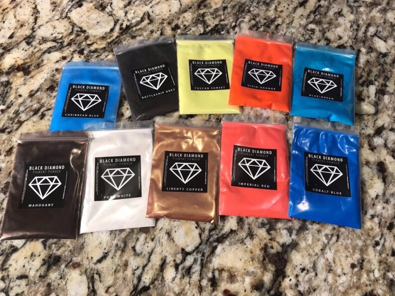 May include: Assortment of 10 small plastic bags containing pigment powder. Each bag has a black label with a diamond logo and the text "Black Diamond Pigment Powder" and the color name. The colors include: Mahogany, Pure White, Liberty Copper, Imperial Red, Cobalt Blue, Caribbean Blue, Battleship Gray, Tuscan Sunset, Vivid Orange, and  Plume Green.
