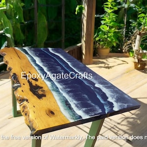Könnte beinhalten: Ein Holztisch mit einer blauen und weißen Epoxidharzplatte, die an Meereswellen erinnert. Der Text "EpoxyAgateCrafts" ist auf dem Tisch sichtbar.