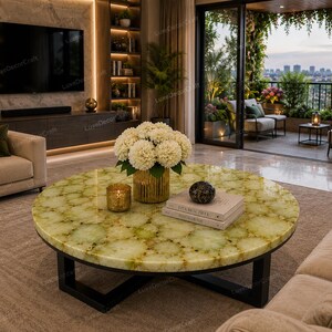 May include: A round coffee table with a green and yellow patterned top and a black metal base. The table is in a living room with a beige sofa, a gold vase with white flowers, and a lit candle. The room has a view of a balcony.