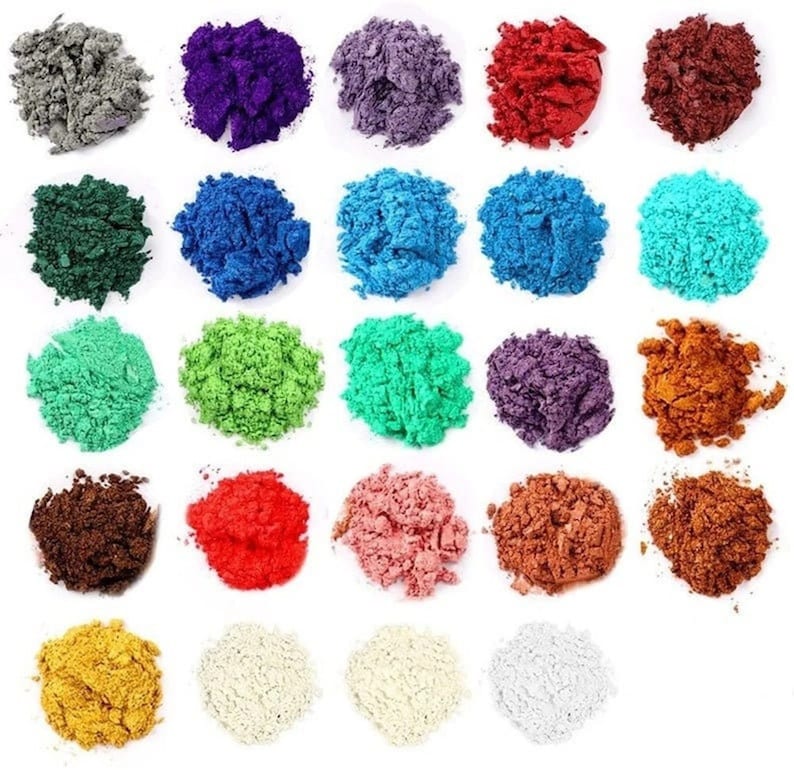 May include: Assortment of 25 vibrant pigment powder colors in small piles on a white background. The colors include red, orange, yellow, green, blue, purple, brown, black, and white.