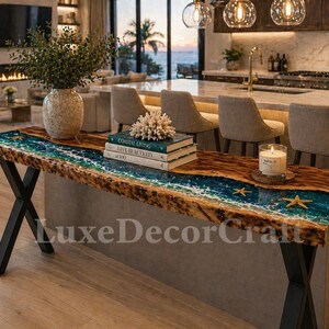 Könnte beinhalten: Ein handgefertigter Konsolentisch mit einer Tischplatte aus Holz mit lebendiger Kante und einem blauen Harzfluss-Design mit eingebetteten Seesternen. Der Tisch hat schwarze Metallbeine und ist mit Büchern, einer Kerze und einem Korallenstück dekoriert. Der Tisch ist ca. 183 cm lang.