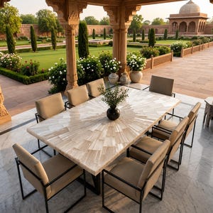 Puede incluir: Una mesa de comedor rectangular con un tablero de piedra de color claro con patrón de rayos de sol y una base de metal negro, rodeada por ocho sillas con asientos tapizados en beige y marcos de metal negro, con un pequeño jarrón negro.