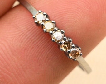 May include: A silver band ring with five small round diamonds. The diamonds are set in a row and are graduated in size, with the largest diamond in the center. The diamonds are a mix of white and yellow.