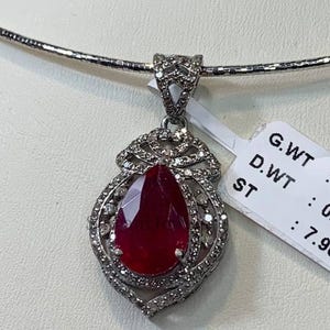 Può includere: Una collana d'argento con un ciondolo che presenta un grande rubino rosso circondato da diamanti più piccoli. Il ciondolo ha la forma di una lacrima. La collana pesa 4,61 grammi e il rubino 0,92 carati. I diamanti sono di 7,96 carati.