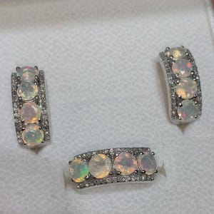 May include: A set of three silver rings with white opals and small diamonds. The rings are all the same style, with a row of opals and diamonds set in a silver band.