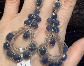 May include: A pair of dangle earrings with a silver setting and blue sapphire stones. The earrings are 3.92ct and weigh 23.560 grams. The tag also says "safayer gold 0.4179ct silv 14.378 gram".