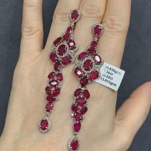 May include: A pair of long, dangling earrings with red ruby gemstones and diamonds set in silver. The earrings are 13.662 grams and feature 2.50 carats of rubies.