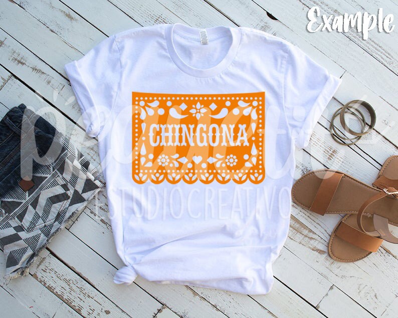 Puede incluir: Camiseta blanca con un dise&ntilde;o de papel recortado naranja que dice "CHINGONA" en texto blanco.