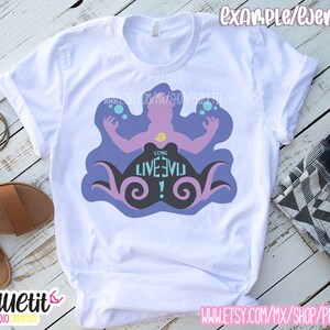 Puede incluir: Camiseta blanca con una silueta morada y azul de un personaje con el texto "Long Live Evil!" impreso en ella.