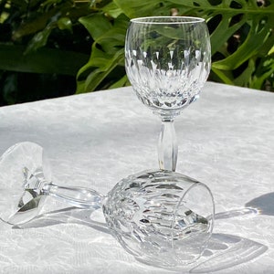 May include: Two clear glass wine glasses with a cut crystal design. The glasses are on a white tablecloth.