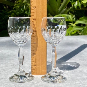 May include: Two clear glass stemmed wine glasses with a cut crystal design. The glasses are on a white tablecloth.