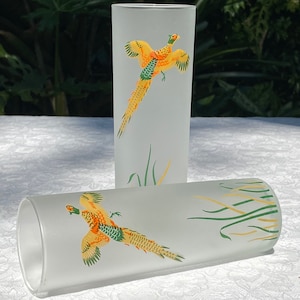 May include: Two frosted glass tumblers with a pheasant design. The glasses are white with a yellow pheasant flying over green grass.