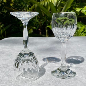 May include: Two clear glass wine glasses, one with a wide bowl and a tall stem, the other with a smaller bowl and a shorter stem.