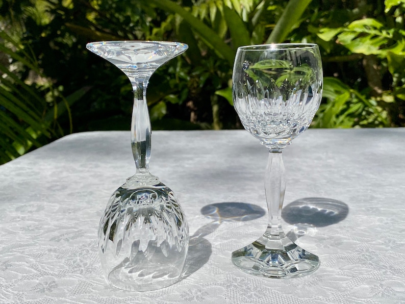 May include: Two clear glass wine glasses, one with a wide bowl and a tall stem, the other with a smaller bowl and a shorter stem.