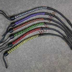 K&ouml;nnte beinhalten: Ein Set aus sechs Lederpeitschen mit verschiedenen farbigen geflochtenen Akzenten. Die Peitschen sind schwarz mit wei&szlig;en, violetten, orangefarbenen, gr&uuml;nen, roten und gelben Akzenten.