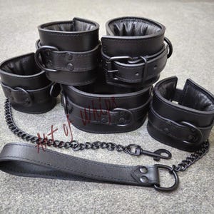 Puede incluir: Conjunto de cuatro ataduras de cuero negro con una correa y una cadena de cuero negro a juego.