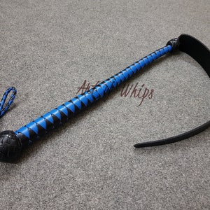 Puede incluir: Un l&aacute;tigo de cuero negro con un mango trenzado azul y negro y una larga correa de cuero negro. El l&aacute;tigo mide aproximadamente 76 cm de largo.