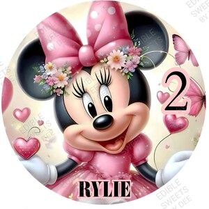 May include: A round, pink Minnie Mouse image with a floral headband, a large bow, and a pink dress. The image includes the name "RYLIE" and the number "2", along with pink hearts and butterflies.