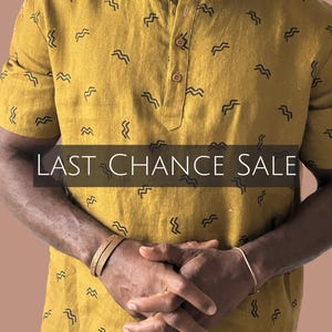 May include: Mustard yellow short-sleeve shirt with a mandarin collar and a wavy black pattern. The shirt has a buttoned placket and is part of a sale. The text "LAST CHANCE SALE" is displayed across the image.