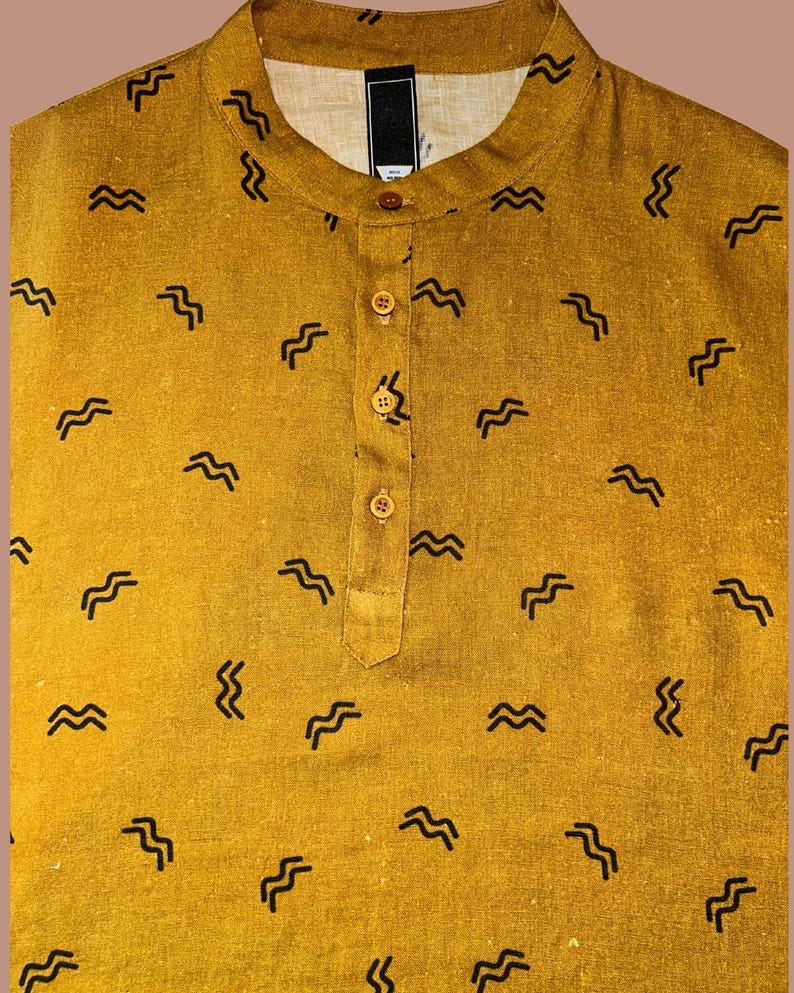 May include: Mustard yellow shirt with a mandarin collar and a button-down placket. The shirt features a repeating pattern of black, wavy lines. The fabric appears to be a textured linen or cotton blend, offering a casual and comfortable look.