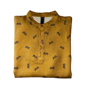 May include: Mustard-colored shirt with a mandarin collar and a button-down placket. The shirt is patterned with small, black, wave-like designs. The shirt is folded neatly, showcasing its design and construction. A casual, everyday garment.