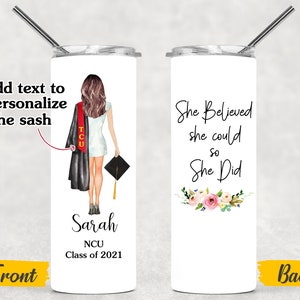 K&ouml;nnte beinhalten: Ein wei&szlig;er Becher mit einer Illustration von schwarzer und roter Abschluss-Kappe und -Kleidung, dem Text "Sarah NCU Class of 2021" und den Worten "She Believed she could so She Did" mit rosa Blumen auf der R&uuml;ckseite.
