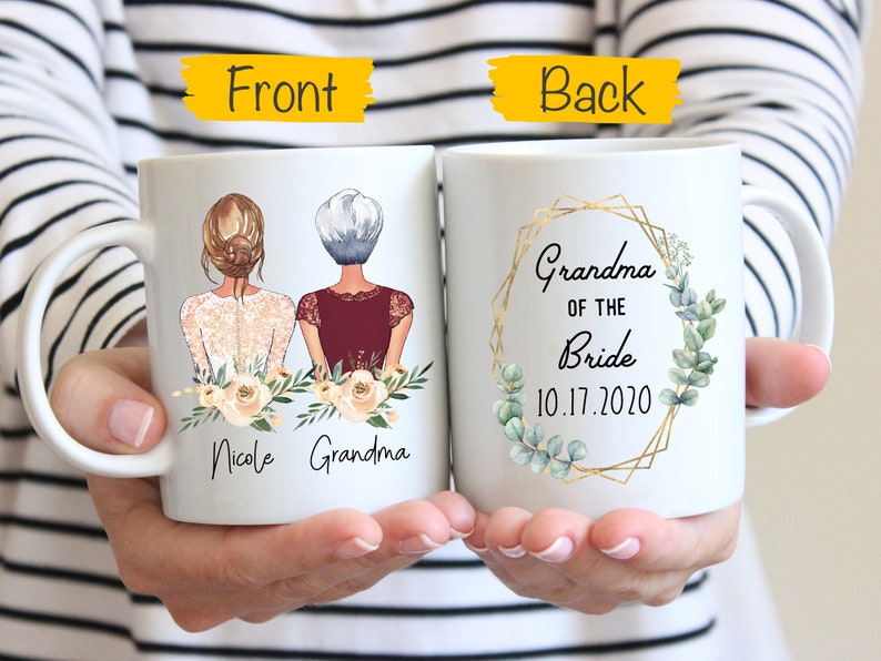 Pode incluir: Caneca de cer&acirc;mica branca com um desenho de duas mulheres, uma com cabelo castanho e outra com cabelo grisalho, com o texto "Nicole Grandma" na frente. A parte de tr&aacute;s da caneca tem uma moldura geom&eacute;trica dourada com folhas verdes e o texto "Grandma of the Bride 10.17.2020".