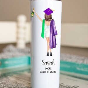K&ouml;nnte beinhalten: Ein wei&szlig;er Edelstahlbecher mit einer Illustration von einer violetten und gr&uuml;nen Abschluss-Kappe und -Robe. Der Text "Sarah NCU Class of 2021" ist auf dem Becher aufgedruckt.