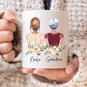 Pode incluir: Caneca de cer&acirc;mica branca com um gr&aacute;fico de duas mulheres com flores e o texto "Nicole Grandma".