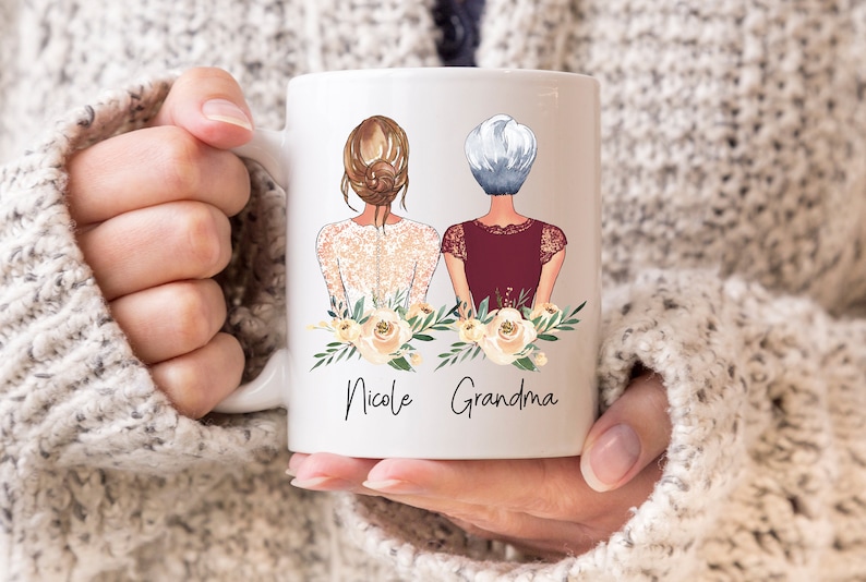 Pode incluir: Caneca de cer&acirc;mica branca com um gr&aacute;fico de duas mulheres com flores e o texto "Nicole Grandma".