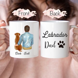 Puede incluir: Taza de cer&aacute;mica blanca con la inscripci&oacute;n "Labrador Dad" y una huella de pata. La parte delantera de la taza tiene un gr&aacute;fico de un hombre y un perro con los nombres "Clark Scott".