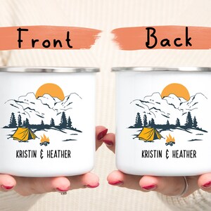 May include: Two white enamel camping mugs with a mountain scene and a yellow tent. The text "Kristin & Heather" is printed on the front of each mug.