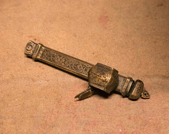 May include: A brass, intricately engraved, decorative object with a floral design. The object has a hinged section and a small, decorative handle.