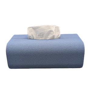 May include: A blue tissue box with a textured finish. The box has a curved design and a rectangular opening at the top, with white tissues protruding.