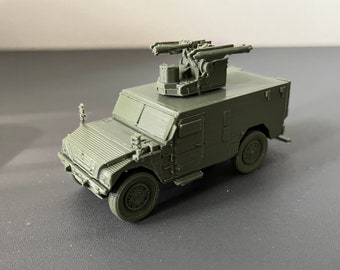 May include: A green military vehicle model with a raised gun turret on top. The vehicle has four wheels and a closed cab.