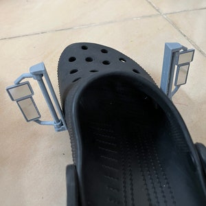 Può includere: Un paio di zoccoli neri con due attacchi a specchietto retrovisore riflettenti grigi.