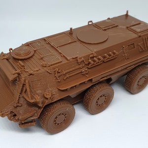 Op de afbeelding: Een bruin plastic model van een gepantserde troepentransporter met een gedetailleerd exterieur en zes wielen.