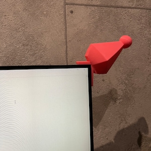 May include: A pink 3D printed geometric object with a rounded top, sitting on top of a computer monitor.