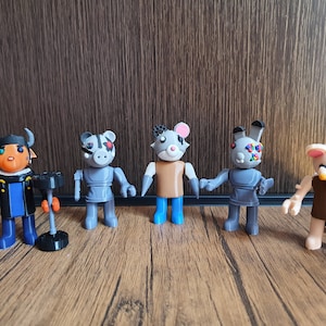 May include: Five small gray, brown, and white plastic figurines of cartoon animals. The figurines are standing on a wooden surface.