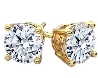 May include: A pair of gold stud earrings with a round, clear diamond-like stone in each earring.