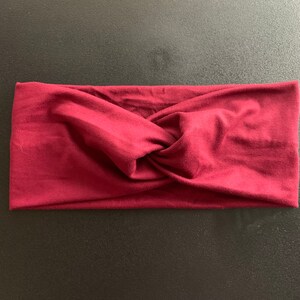 Puede incluir: Una diadema anudada de color burdeos hecha de tela suave.