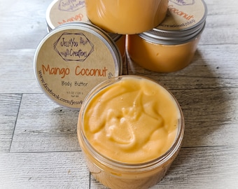 May include: A glass jar filled with mango coconut body butter. The jar has a brown label with the text "Jess You Creations" and "Mango Coconut Body Butter" in white. The label also includes the website address "www.facebook.com/jess4" and the weight "4.5 oz / 128 g".